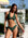 Woman in a green bikini standing outdoors with a blurred background
